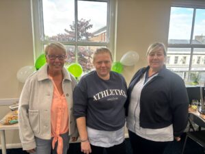 Group of three of our staff members standing in the office with balloons in the background.