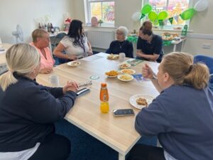 Group of six including staff and service users enjoying their Macmillan coffee morning.